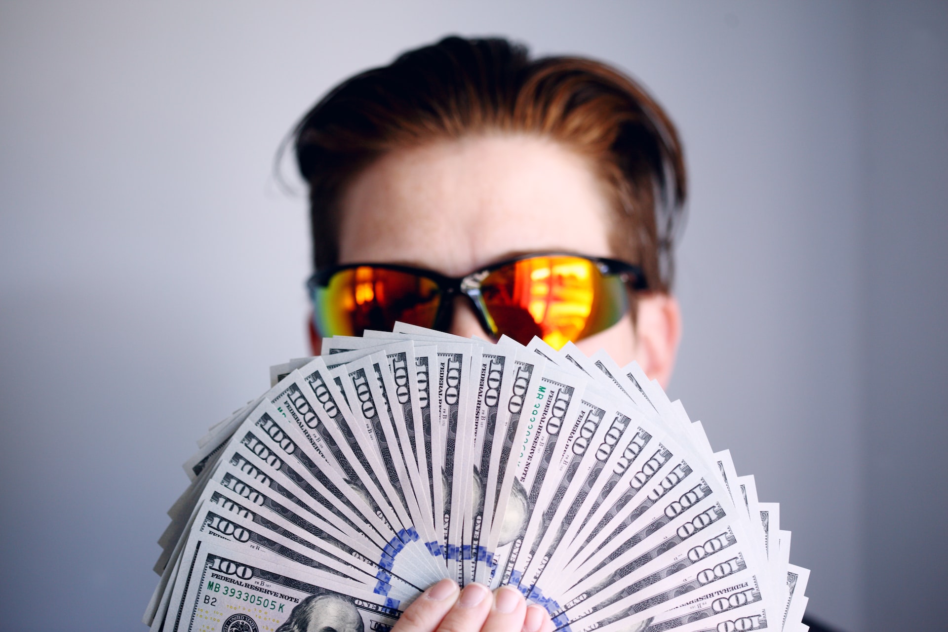 Person with sunglasses holding lots of money.